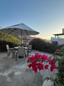 a table and chairs and an umbrella and flowers at Casa Tara in Taganga