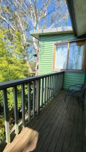 a porch of a green house with a bench on it at The Black Cockatoo - Secret Garden Treetops Home in Katoomba