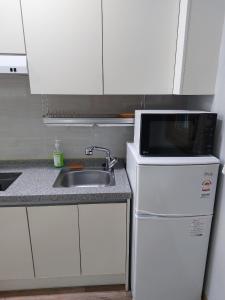 a small kitchen with a sink and a microwave at Gyeongpoen Pension in Gangneung