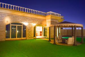 uma casa com um relvado verde e um gazebo em ارجان قرطبة للشقق المخدومة em Al Khobar