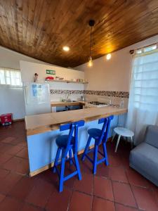 a kitchen with a counter with two blue bar stools at La Estación de Tomine in Guatavita