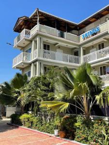 a large white building with palm trees in front of it at Three Kings Hotel in Vertières