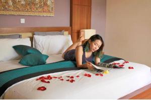 Une femme qui se couche sur un lit avec des fleurs sur lui dans l'établissement Ubud City 2BR Private Pool Villa in Ubud, à Ubud