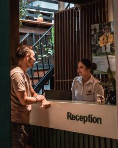 a man and a woman standing behind a reception desk at THIS IS COLOMBIA HOSTEL in San Gil