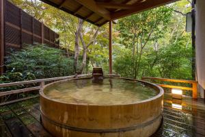 una gran bañera de madera en una terraza con árboles en Jinya Ryokan, en Hadano