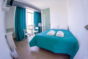 Un dormitorio con una cama verde y una mesa con sillas. en LAS GAVIOTAS DE PARACAS en Paracas
