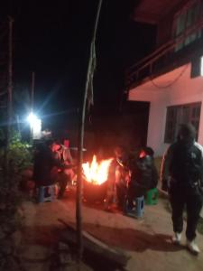 a group of people standing around a fire at night at Unique point home stay in Nagarkot