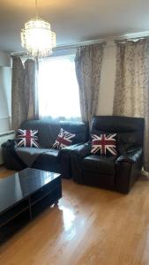 a living room with a black leather couch with british pillows at 24 Kingsley gardens in Chingford
