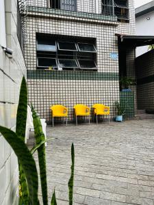 eine Terrasse mit gelben Stühlen und ein Gebäude in der Unterkunft Center Hostel Sp in São Paulo