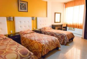 three beds in a hotel room with orange walls at Gran Hotel Canada in Santa Cruz de la Sierra