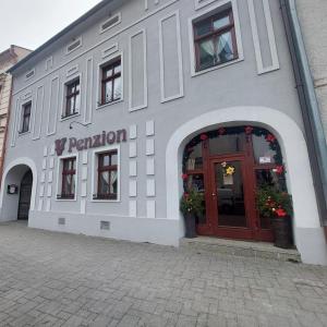 un bâtiment blanc avec une porte rouge dans une rue dans l'établissement Schiller Haus&Restaurant, à Spišská Belá