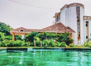 a large building with a swimming pool in front of it at Sunshine Beach House in Navalur