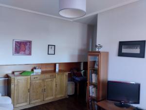 ein Wohnzimmer mit einem TV und einem Holzschrank in der Unterkunft Sweets Suites in Espinho