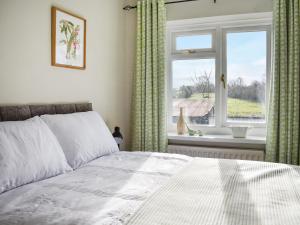 a bedroom with a bed and a window with curtains at Heather Cottage in Bishop Auckland