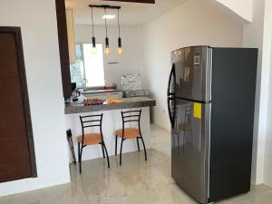 a kitchen with a refrigerator and a counter with stools at Brisa Blanca in Punta Blanca