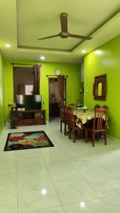 comedor con paredes verdes, mesa y sillas en Yamad Homestay Langkawi, en Kuah