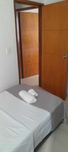 a bed with two white towels and a wooden door at habitación con baño en bucaramanga-cerca sena-uis in Bucaramanga