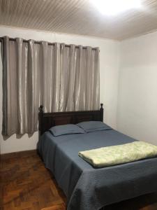 a bedroom with a bed and a window with curtains at Tiago Barreto in Poços de Caldas