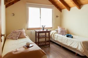 two beds in a room with a window at Bandurrias in Esquel