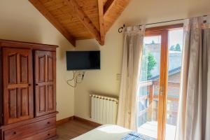 a bedroom with a bed and a tv and a window at Bandurrias in Esquel