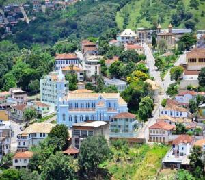 une ville avec un bâtiment bleu sur une colline dans l'établissement Pousada Economic Pitangui, à Pitangui