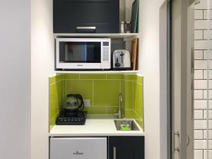 a small kitchen with a microwave and a sink at The Frome Studio in Frome