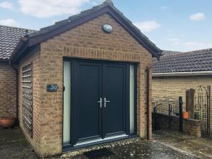 uma porta de garagem preta numa casa de tijolos em The Frome Studio em Frome