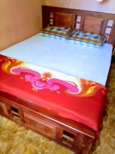 una cama con una manta roja con una flor pintada en ella en Linu Villa, en Hikkaduwa