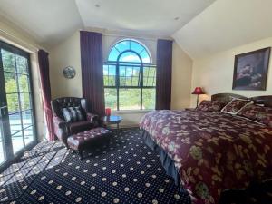 um quarto com uma cama, uma cadeira e janelas em Fontainebleau Luxury B&B em Hanmer Springs