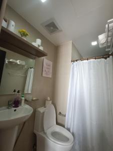uma casa de banho com um WC branco e um lavatório. em Magen's Place em Bacolod