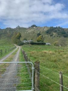 uma vedação ao lado de uma estrada num campo em Hill top view farm stay em Uruti