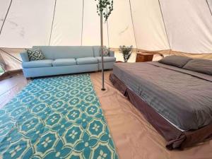 een slaapkamer met een bed en een bank in een tent bij North Shore Glamping / Camping Laie, Oahu, Hawaii in Laie