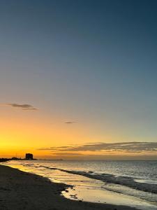 a beach with the sun setting in the ocean at Depa tipo estudio cerca del mar y en la ciudad en Puerto Progreso in Progreso