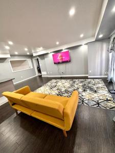 Golden Beautiful Home في برامبتون: غرفة معيشة مع أريكة صفراء وتلفزيون بشاشة مسطحة