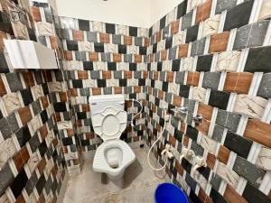 a bathroom with a toilet and a tiled wall at HOTEL AMARNATH Bakkhali in Bakkhali