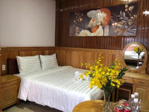 a bedroom with a bed and a mirror and flowers at KHÁNH AN HOTEL in Da Lat