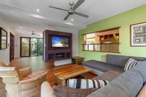 ein Wohnzimmer mit einem Sofa und einem TV in der Unterkunft Leilani Melia - stylish 3 bedroom villa on Four Mile Beach in Port Douglas