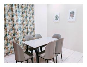 a dining room with a white table and chairs at Richmond Residence in Kuching
