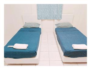 twee bedden in een kamer met blauwe lakens en kussens bij Richmond Residence in Kuching