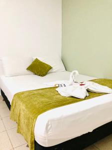 2 Betten in einem Hotelzimmer mit Handtüchern darauf in der Unterkunft Laurel plaza in Montería