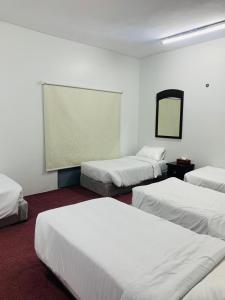 a room with three beds and a mirror at لينا للوحدات السكنية المفروشة in Al Madinah