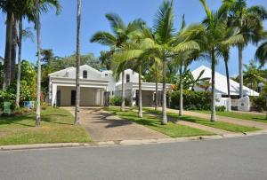 a white house with palm trees in front of it at The Condo - A Spacious Villa Near Beach and Town in Port Douglas
