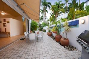 a patio with a table and chairs and palm trees at The Condo - A Spacious Villa Near Beach and Town in Port Douglas