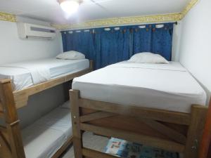 two bunk beds in a small room with blue curtains at Hotel Alto de los Nogales in Barranquilla