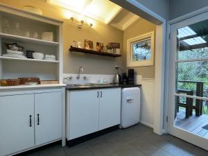 a kitchen with white cabinets and a sink at Burradoo Studio in Leura