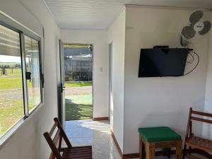 Zimmer mit einem TV, Stühlen und einem Fenster in der Unterkunft Posada campo bello in Quebracho