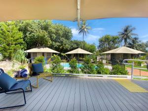 a deck with chairs and umbrellas and a pool at Magnetic Glamping Tent 7 in Nelly Bay