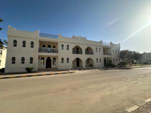 un gran edificio blanco al lado de una calle en Samharam Resort Salalah en Salalah