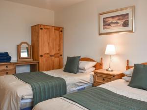 Woodville Cottage في كوكيرماوث: غرفة نوم بسريرين ومرآة