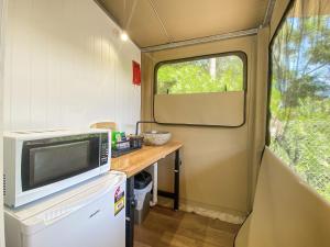 a kitchen with a microwave and a table in a caravan at Magnetic Glamping Tent 10 in Nelly Bay